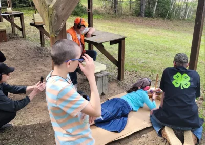 girl shooting from ground with boy and men watching